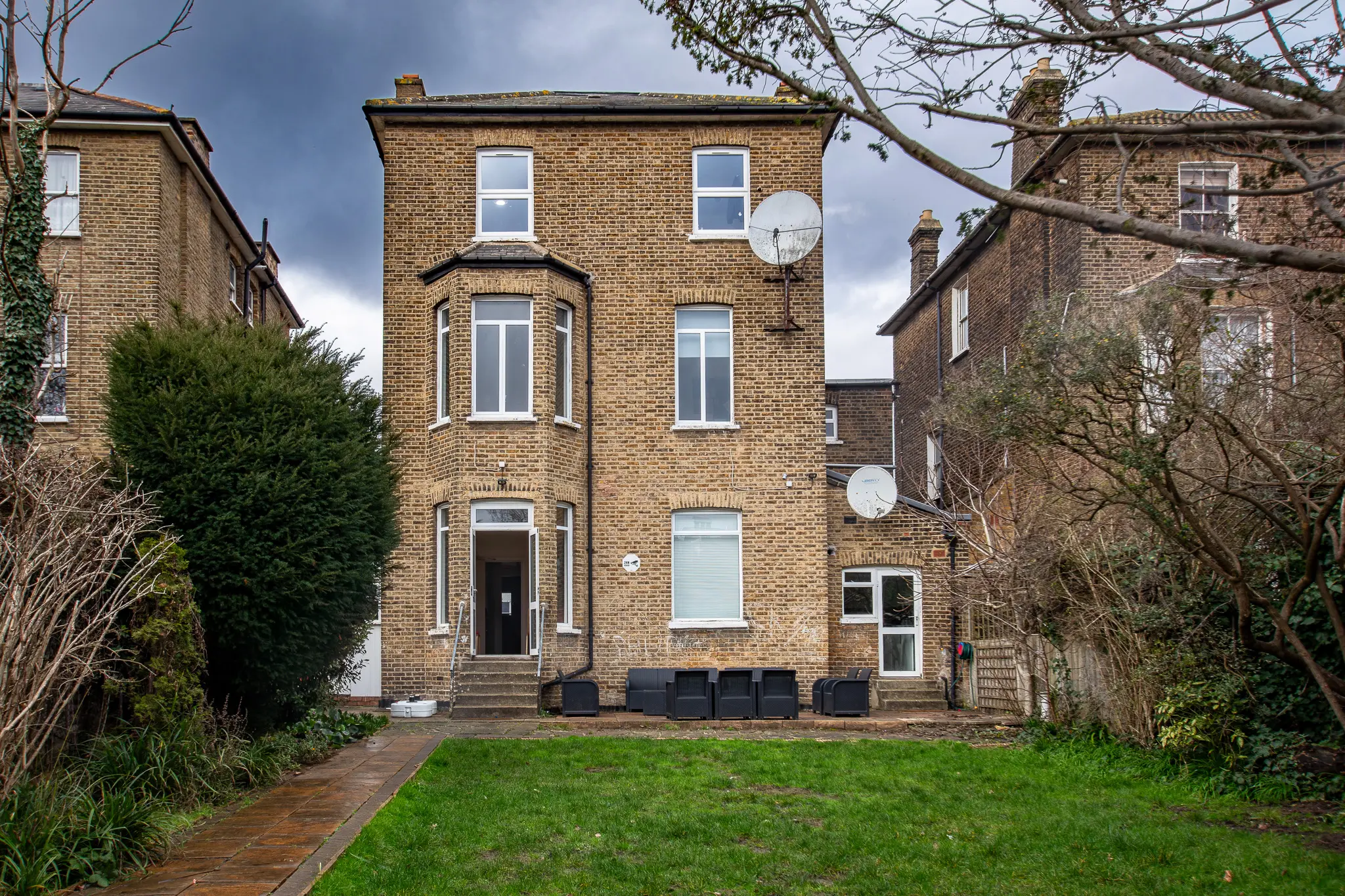 Rear exterior real estate photography showing a house and green garden in London
